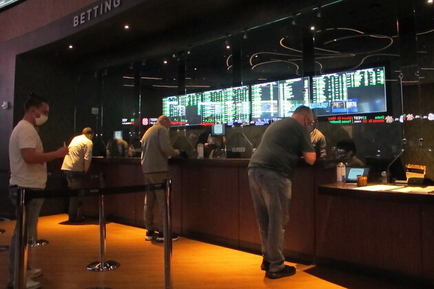 People line up to make sports bets at the Borgata casino in Atlantic City NJ on Friday March 19, 2021, the first full day of the NCAA March Madness tournament. Last year, it was March sadness as the NCAA college basketball tournament got canceled days before it was supposed to start, due to the coronavirus.  (AP Photo/Wayne Parry)