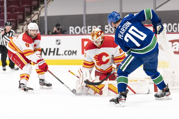 Calgary Flames Christopher Tanev (8) clears the puck after Calgary Flames goaltender Jacob Markstrom (25) stops Vancouver Canucks Tanner Pearson (70) during an NHL hockey game, Thursday, Feb. 11, 2021, in Vancouver, Canada. (AP Photo/Rich Lam)