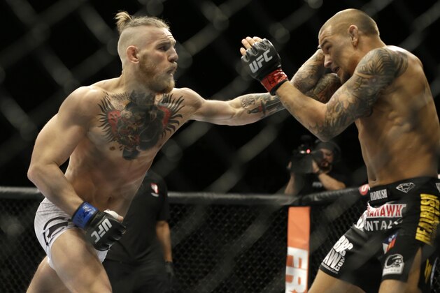 FILE - In this Sept. 27, 2014, file photo, Conor McGregor, left, and Dustin Poirier, exchange hits during their mixed martial arts bout in Las Vegas. UFC President Dana White confirmed to The Associated Press on Thursday, Nov. 19,2020, that McGregor has officially signed an agreement for a probable 155-pound fight with Poirier, ending McGregor's latest retirement from mixed martial arts. (AP Photo/John Locher, File)
