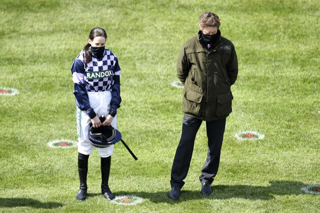 Jockey Rachael Blackmore, left, stands in the parade ring during the two minute silence before the first race on the third day of the Grand National Horse Racing meeting at Aintree racecourse, near Liverpool, England, Saturday April 10, 2021. (Peter Powell/Pool via AP)