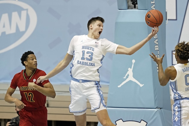 North Carolina forward Walker Kessler (13) grabs a rebound over Louisville forward JJ Traynor (12) while North Carolina guard Anthony Harris (0) reaches in during the first half of an NCAA college basketball game in Chapel Hill, N.C., Saturday, Feb. 20, 2021. (AP Photo/Gerry Broome)