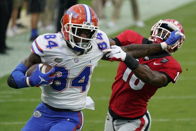 FILE - Florida tight end Kyle Pitts (84) tires to get past Georgia defensive back Lewis Cine (16) after a reception during the first half of an NCAA college football game in Jacksonville, Fla., in this Saturday, Nov. 7, 2020, file photo. Kyle Pitts is arguably the most dynamic playmaker in the NFL draft, a versatile tight end who will try to impress league executives in person during Florida's pro day Wednesday, March 31, 2021.  (AP Photo/John Raoux, File)