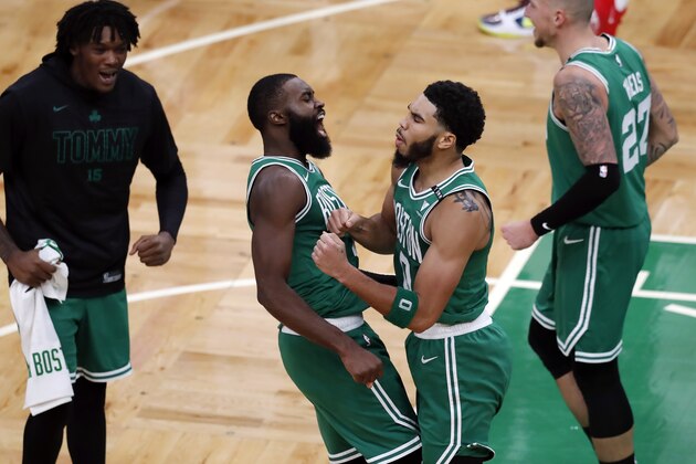 Boston Celtics' Jayson Tatum (0) celebrates with Jaylen Brown (7) after making the go-ahead basket with less than a second on the clock during the second half of an NBA basketball game against the Milwaukee Bucks, Wednesday, Dec. 23, 2020, in Boston. (AP Photo/Michael Dwyer)