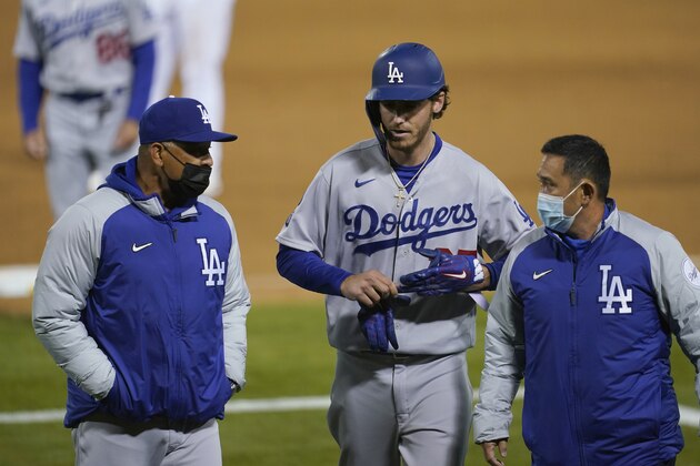 Los Angeles Dodgers' Cody Bellinger, center, walks off the field as he leaves the game with manager Dave Roberts, left, and a trainer during the ninth inning of a baseball game against the Oakland Athletics in Oakland, Calif., Monday, April 5, 2021. (AP Photo/Jeff Chiu)