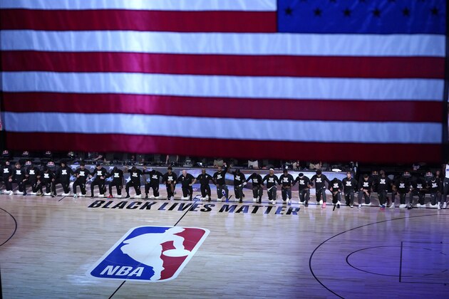 FILE - Members of the Orlando Magic and Brooklyn Nets kneel around a Black Lives Matter logo during the national anthem before the start of an NBA basketball game in Lake Buena Vista, Fla., in this Friday, July 31, 2020, file photo. As the NBA neared its restart in late July, its players vowed to keep the calls for social justice reform at the forefront in the wake of the deaths of George Floyd and Breonna Taylor.(AP Photo/Ashley Landis, Pool, File)