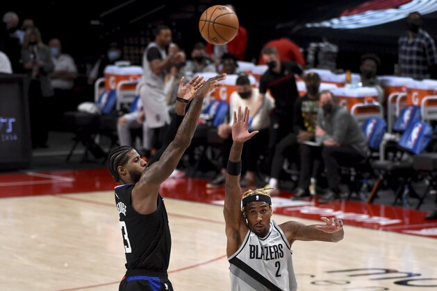 Los Angeles Clippers guard Paul George, left, hits a shot over Portland Trail Blazers forward Rondae Hollis-Jefferson, right, during the first half of an NBA basketball game in Portland, Ore., Tuesday, April 20, 2021. (AP Photo/Steve Dykes)
