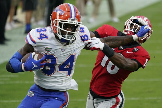 FILE - Florida tight end Kyle Pitts (84) tires to get past Georgia defensive back Lewis Cine (16) after a reception during the first half of an NCAA college football game in Jacksonville, Fla., in this Saturday, Nov. 7, 2020, file photo. Kyle Pitts is arguably the most dynamic playmaker in the NFL draft, a versatile tight end who will try to impress league executives in person during Florida's pro day Wednesday, March 31, 2021.  (AP Photo/John Raoux, File)