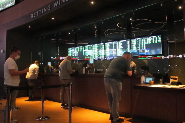 People line up to make sports bets at the Borgata casino in Atlantic City NJ on Friday March 19, 2021, the first full day of the NCAA March Madness tournament. Last year, it was March sadness as the NCAA college basketball tournament got canceled days before it was supposed to start, due to the coronavirus.  (AP Photo/Wayne Parry)