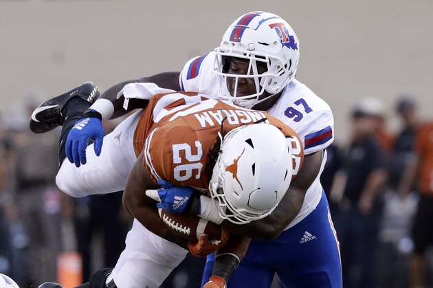 Texas running back Keaontay Ingram (26) is up ended by Louisiana Tech safety L'Jarius Sneed (1) and defensive end Milton Williams (97) on a run during the first half of an NCAA college football game, Saturday, Aug. 31, 2019, in Austin, Texas. (AP Photo/Eric Gay)