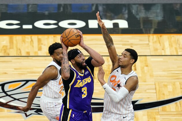 Los Angeles Lakers forward Anthony Davis (3) takes shot as he gets between Orlando Magic guard Chasson Randle, left, and forward Chuma Okeke (3)during the first half of an NBA basketball game, Monday, April 26, 2021, in Orlando, Fla. (AP Photo/John Raoux)