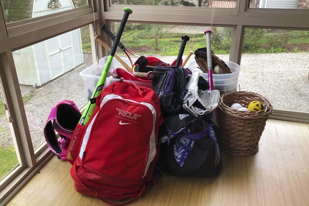 FILE - In this April 14, 2020, file photo, baseball and softball bags for Colin and Catherine Graves lie untouched in Monroeville, Pa. Doctors, scientists and sports leaders are outlining the path back to playing fields for children in grassroots sports -- an exercise that could inform major organizations on how to get their industries up and running as well in the midst of the COVID-19 pandemic. (AP Photo/Will Graves, File)