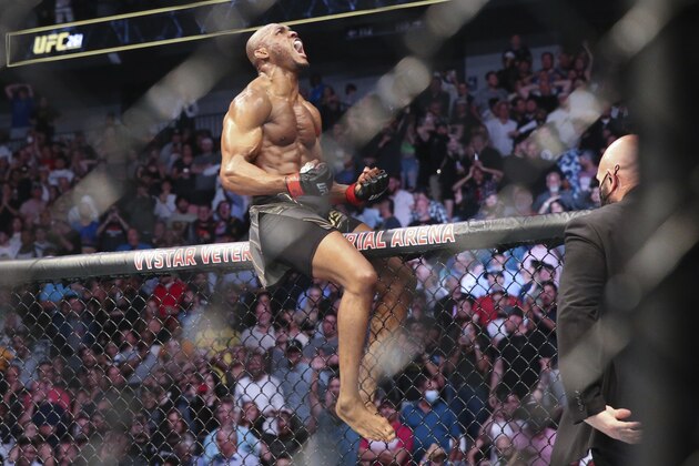 Kamaru Usman celebrates his win atop the octagon fence after a UFC 261 mixed martial arts bout against Jorge Masvidal early Sunday, April 25, 2021, in Jacksonville, Fla. (AP Photo/Gary McCullough)