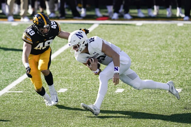 Northwestern quarterback Peyton Ramsey (12) runs from Iowa linebacker Nick Niemann (49) during the first half of an NCAA college football game, Saturday, Oct. 31, 2020, in Iowa City, Iowa. (AP Photo/Charlie Neibergall)