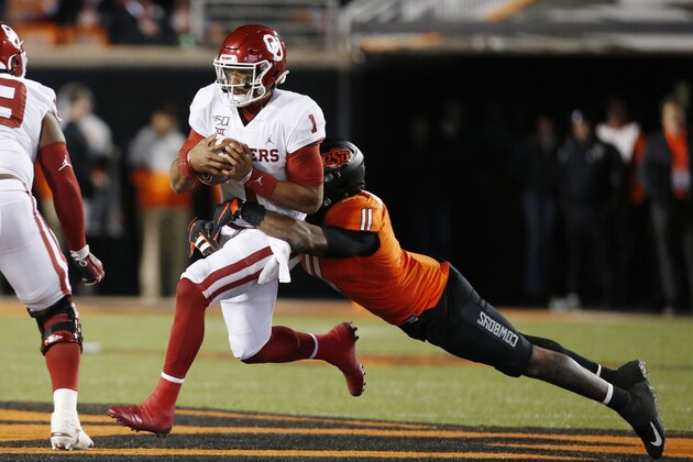 Oklahoma quarterback Jalen Hurts (1) is tackled by Oklahoma State linebacker Amen Ogbongbemiga (11) during an NCAA college football game in Stillwater, Okla., Saturday, Nov. 30, 2019. (AP Photo/Sue Ogrocki)