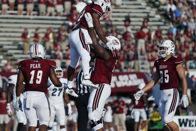Massachusetts running back Bilal Ally, center top, celebrates his touchdown with offensive lineman Larnel Coleman, center bottom, during the first half of an NCAA college football game against Duquesne in Amherst, Mass., Saturday, Aug. 25, 2018. (AP Photo/Michael Dwyer)
