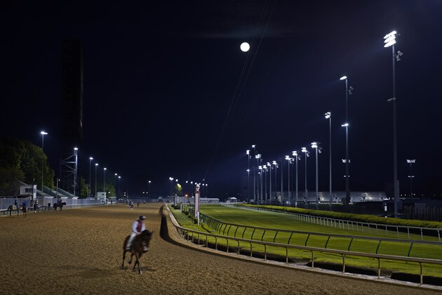 A horse works out under the setting full moon at Churchill Downs Tuesday, April 27, 2021, in Louisville, Ky. The 147th running of the Kentucky Derby is scheduled for Saturday, May 1. (AP Photo/Charlie Riedel)