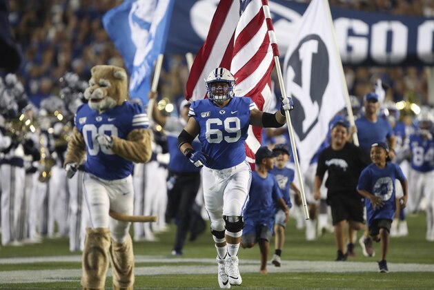 BYU offensive lineman Tristen Hoge (69) brings the American flag onto the field before an NCAA college football game against Utah, Thursday, Aug. 29, 2019, in Provo, Utah. (AP Photo/George Frey)