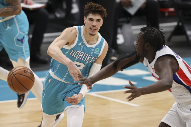 Charlotte Hornets guard LaMelo Ball, left, passes around Detroit Pistons forward Sekou Doumbouya, right,  in the first half of an NBA basketball game in Charlotte, N.C., Saturday, May 1, 2021. (AP Photo/Nell Redmond)