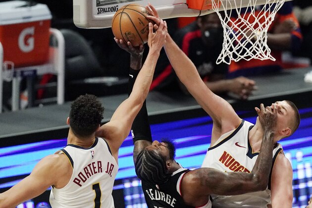 Los Angeles Clippers guard Paul George, center, hits Denver Nuggets center Nikola Jokic, right, in the face as he shoots as forward Michael Porter Jr. defends during the first half of an NBA basketball game Saturday, May 1, 2021, in Los Angeles. (AP Photo/Mark J. Terrill)