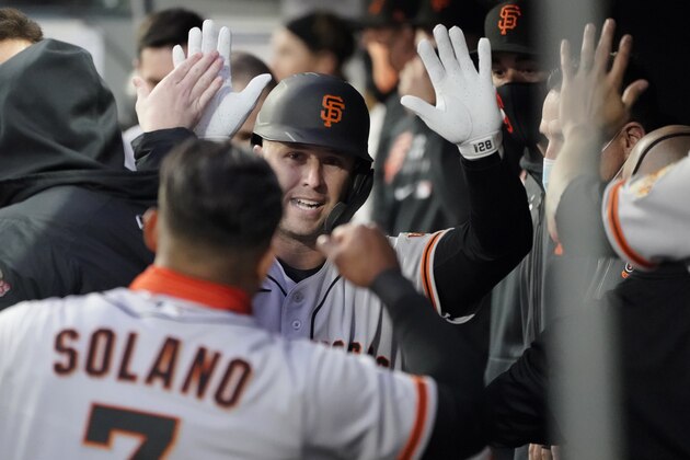 San Francisco Giants' Buster Posey, center, is greeted in the dugout by Donovan Solano (7) after Posey hit a solo home run during the second inning of the team's baseball game against the Seattle Mariners, Thursday, April 1, 2021, in Seattle. (AP Photo/Ted S. Warren)
