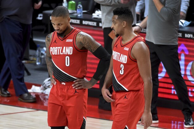 Portland Trail Blazers guard Damian Lillard, left, speaks with guard CJ McCollum, right, during the second half of an NBA basketball game in Portland, Ore., Saturday, Dec. 26, 2020. The Blazers won 128-126 in overtime. (AP Photo/Steve Dykes)