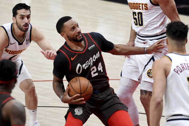 Portland Trail Blazers forward Norman Powell, middle, drives to the basket on Denver Nuggets guard Facundo Campazzo, left, and forward Michael Porter Jr., right, during the first half of an NBA basketball game in Portland, Ore., Sunday, May 16, 2021. (AP Photo/Steve Dykes)