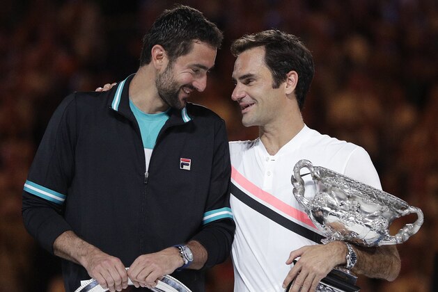 Switzerland's Roger Federer, right, holds his winner's trophy as he talks with Croatia's Marin Cilic following the men's singles final at the Australian Open tennis championships in Melbourne, Australia, Sunday, Jan. 28, 2018. (AP Photo/Dita Alangkara)