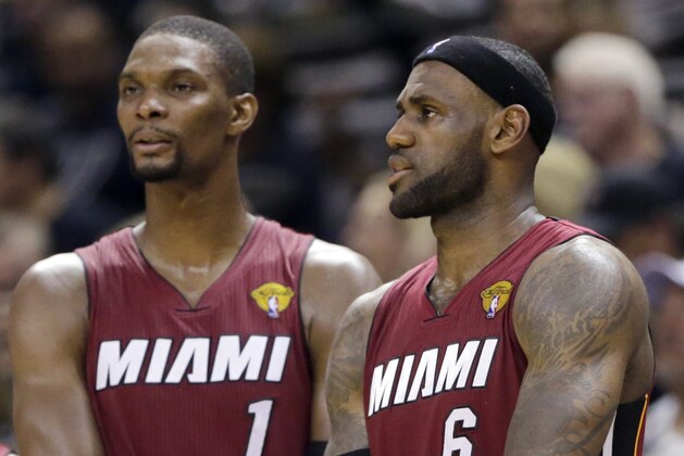 Miami Heat center Chris Bosh (1) and forward LeBron James (6) watch from the sideline against the San Antonio Spurs during the first half in Game 1 of the NBA basketball finals on Thursday, June 5, 2014, in San Antonio. (AP Photo/Eric Gay)