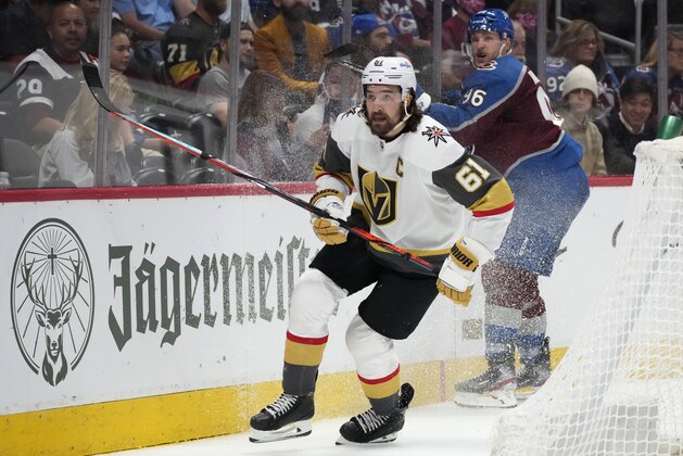 Vegas Golden Knights right wing Mark Stone, front, pursues the puck after checking Colorado Avalanche right wing Mikko Rantanen during the second period of Game 5 in an NHL hockey Stanley Cup second-round playoff series Tuesday, June 8, 2021, in Denver. The Golden Knights won 3-2 in overtime. (AP Photo/David Zalubowski)