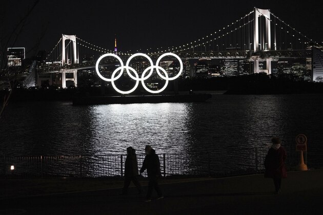People walk near the Olympic rings displayed in the water off the Odaiba Marine Park on Wednesday, March 3, 2021, in Tokyo. (AP Photo/Eugene Hoshiko)