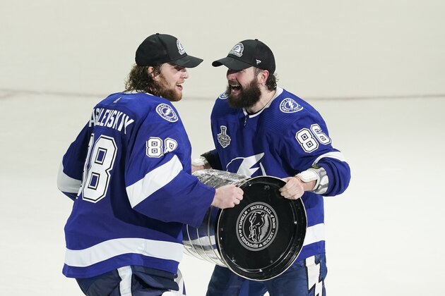 Tampa Bay Lightning right wing Nikita Kucherov (86) hands the Stanley Cup to goaltender Andrei Vasilevskiy after Game 5 of the NHL hockey Stanley Cup finals against the Montreal Canadiens, Wednesday, July 7, 2021, in Tampa, Fla. (AP Photo/Gerry Broome)