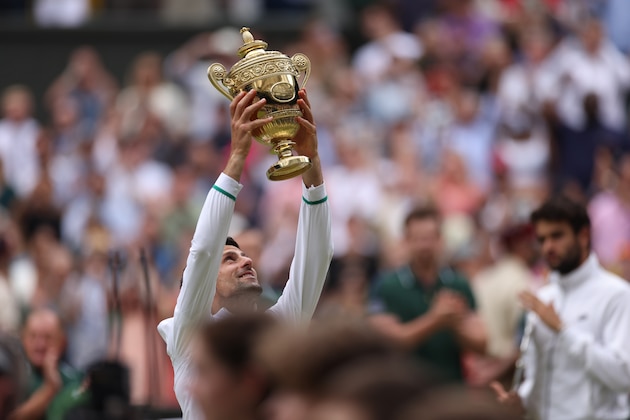 Serbia's Novak Djokovic holds the winner's trophy and celebrates his victory over Italy's Matteo Berrettini during the men's singles final on day thirteen of the Wimbledon Tennis Championships in London, Sunday, July 11, 2021. (Steve Paston/Pool Via AP)