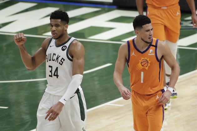 Milwaukee Bucks forward Giannis Antetokounmpo (34) celebrates in front of Phoenix Suns guard Devin Booker (1) at the end of Game 4 of basketball's NBA Finals Wednesday, July 14, 2021, in Milwaukee. (AP Photo/Aaron Gash)