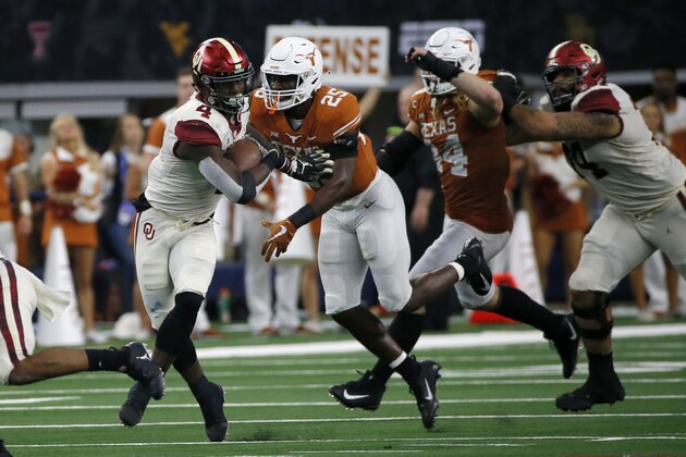 Oklahoma Sooners running back Trey Sermon (4) tries to avoid a tackle by Texas Longhorns safety B.J. Foster (25) during the second half of the NCAA Big 12 Conference football championship, Saturday, Dec. 1, 2018, in Arlington, Texas. Oklahoma defeated Texas 39-27. (AP Photo/Roger Steinman)