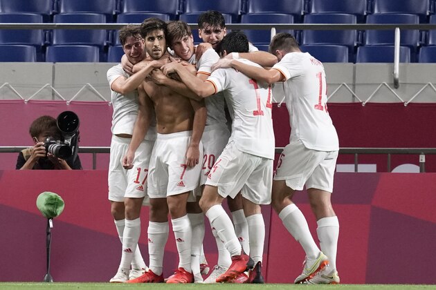 Teammates embrace Spain's Marco Asensio after he scored his side's winning goal against Japan in a men's semifinal soccer match at the 2020 Summer Olympics, Tuesday, Aug. 3, 2021, in Saitama, Japon. (AP Photo/Martin Mejia)