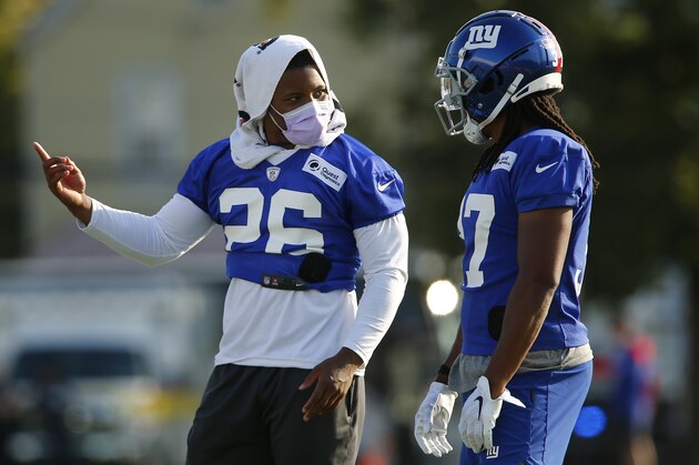 Saquon Barkley, left, who is on the physically unable to perform list, talks with fellow running back Gary Brightwell during the New York Giants' NFL football training camp practice at Eddie Moraes Stadium, Saturday, July 31, 2021, in Newark, N.J. (AP Photo/John Munson)