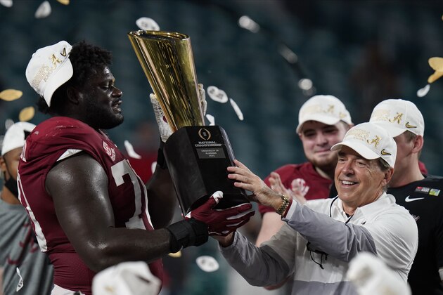Alabama head coach Nick Saban and offensive lineman Alex Leatherwood hold the trophy after their win against Ohio State in an NCAA College Football Playoff national championship game, Tuesday, Jan. 12, 2021, in Miami Gardens, Fla. Alabama won 52-24. (AP Photo/Chris O'Meara)