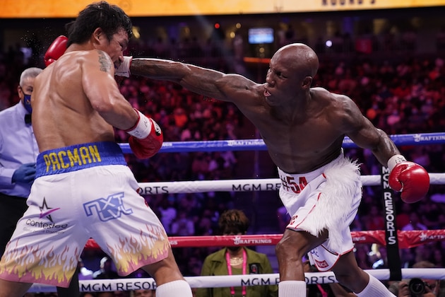 Yordenis Ugas, right, of Cuba, reaches in to hit Manny Pacquiao, of the Philippines, in a welterweight championship boxing match Saturday, Aug. 21, 2021, in Las Vegas. (AP Photo/John Locher)