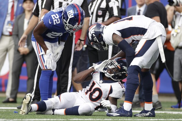 New York Giants' Adoree' Jackson (22) and Denver Broncos' Courtland Sutton, right, check on Jerry Jeudy (10) after Jeudy was injured during the second half of an NFL football game Sunday, Sept. 12, 2021, in East Rutherford, N.J. (AP Photo/Adam Hunger)