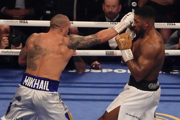 Oleksandr Usyk of Ukraine, left, hits Anthony Joshua of Britain during their WBA (Super), WBO and IBF boxing title bout at the Tottenham Hotspur Stadium in London, Saturday, Sept. 25, 2021. (AP Photo/Frank Augstein)