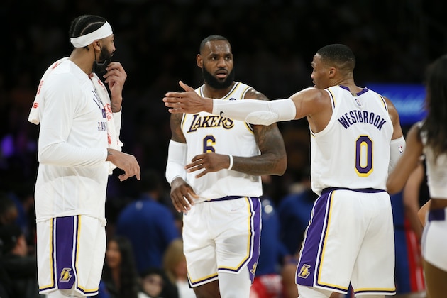 Los Angeles Lakers forwards Anthony Davis, left, and LeBron James, center, talk with guard Russell Westbrook during a timeout in the second half of an NBA basketball game against the Detroit Pistons Sunday, Nov. 28, 2021, in Los Angeles. (AP Photo/Alex Gallardo)