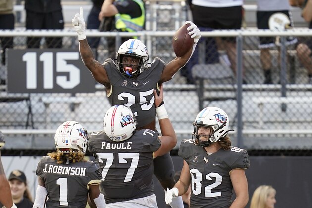 Central Florida running back Johnny Richardson (25) celebrates his 17-yard touchdown pass against Connecticut with teammates Jaylon Robinson (1), Lokahi Pauole (77) and Alec Holler (82) during the first half of an NCAA college football game, Saturday, Nov. 20, 2021, in Orlando, Fla. (AP Photo/John Raoux)