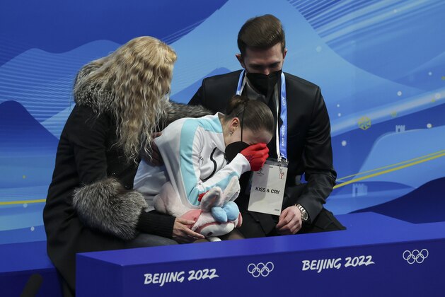 BEIJING, CHINA - FEBRUARY 17: Kamila Valieva of Russia reacts to her score with coach Eteri Tutberidze (L) and Daniil Gleikhengauz (R) at 'Kiss and Cry' during the Women Single Skating Free Skating on day thirteen of the Beijing 2022 Winter Olympic Games at Capital Indoor Stadium on February 17, 2022 in Beijing, China. (Photo by Jean Catuffe/Getty Images)