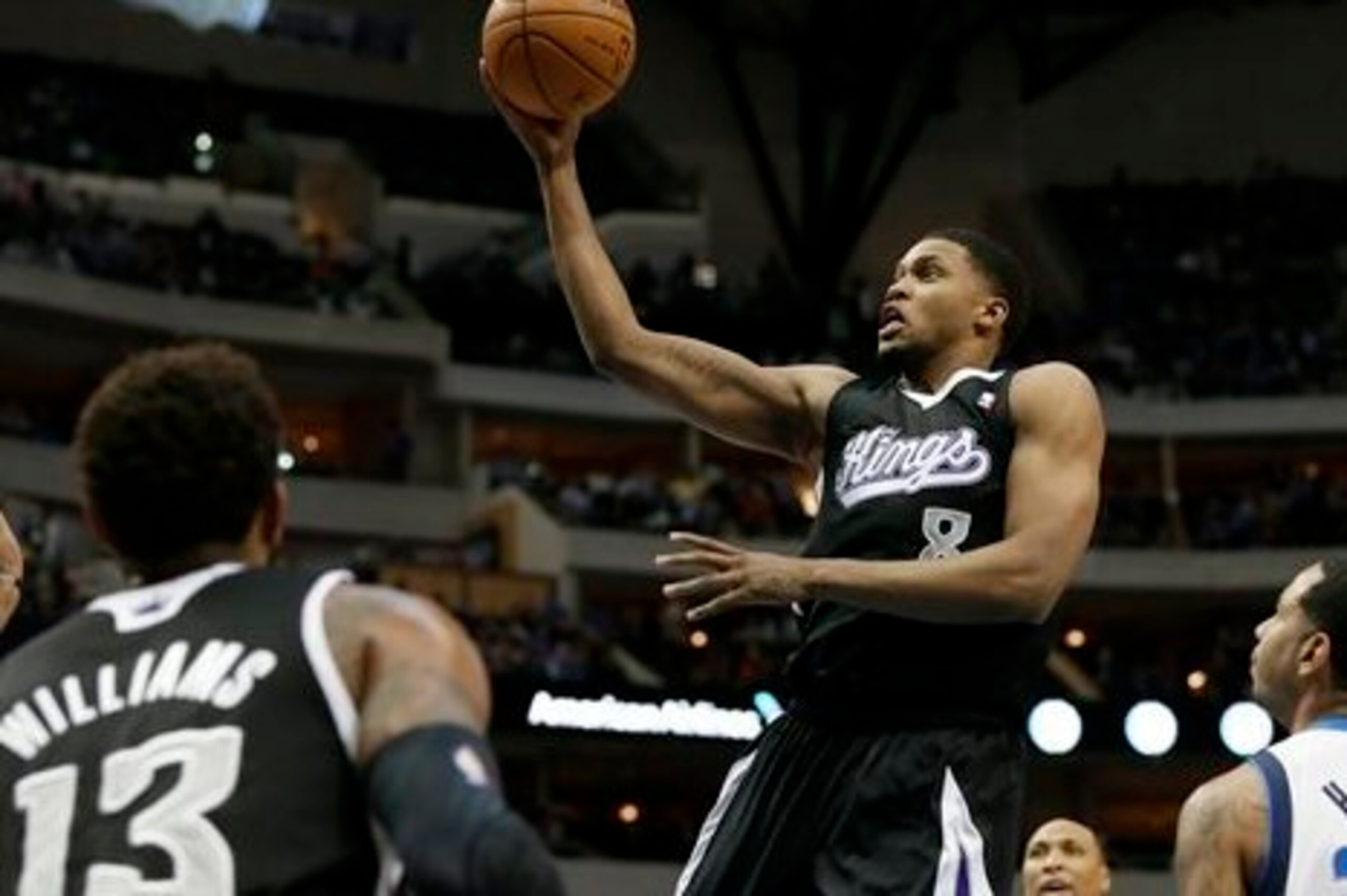 Sacramento Kings' Derrick Williams (13) and Dallas Mavericks' Devin Harris, right, watch as the Kings' Rudy Gay (8) breaks to the basket for a shot in the first half of an NBA basketball game, Saturday, March 29, 2014, in Dallas. (AP Photo/Tony Gutierrez)