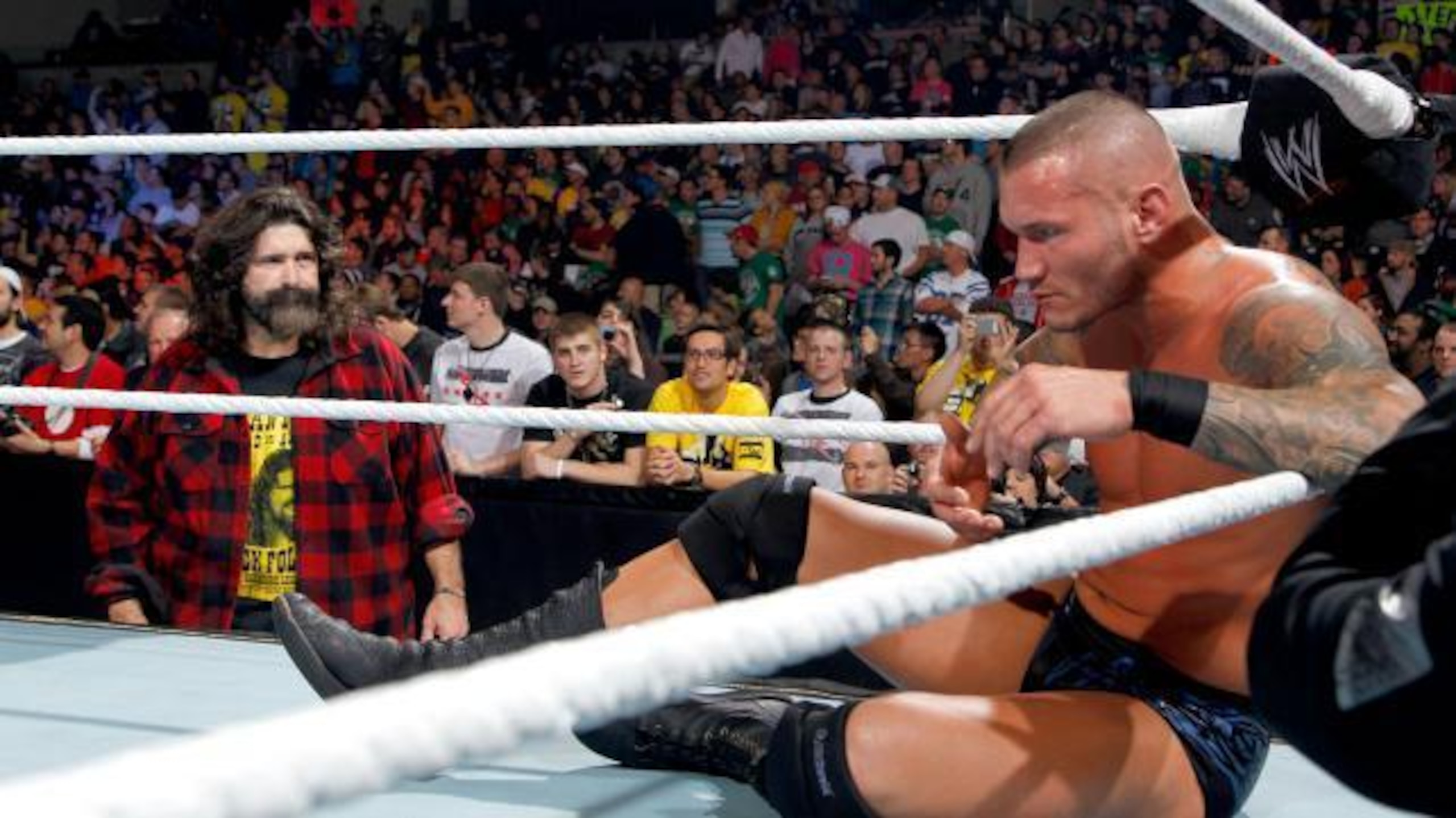 A disappointed Mick Foley looks on as Randy Orton sulks in the corner.