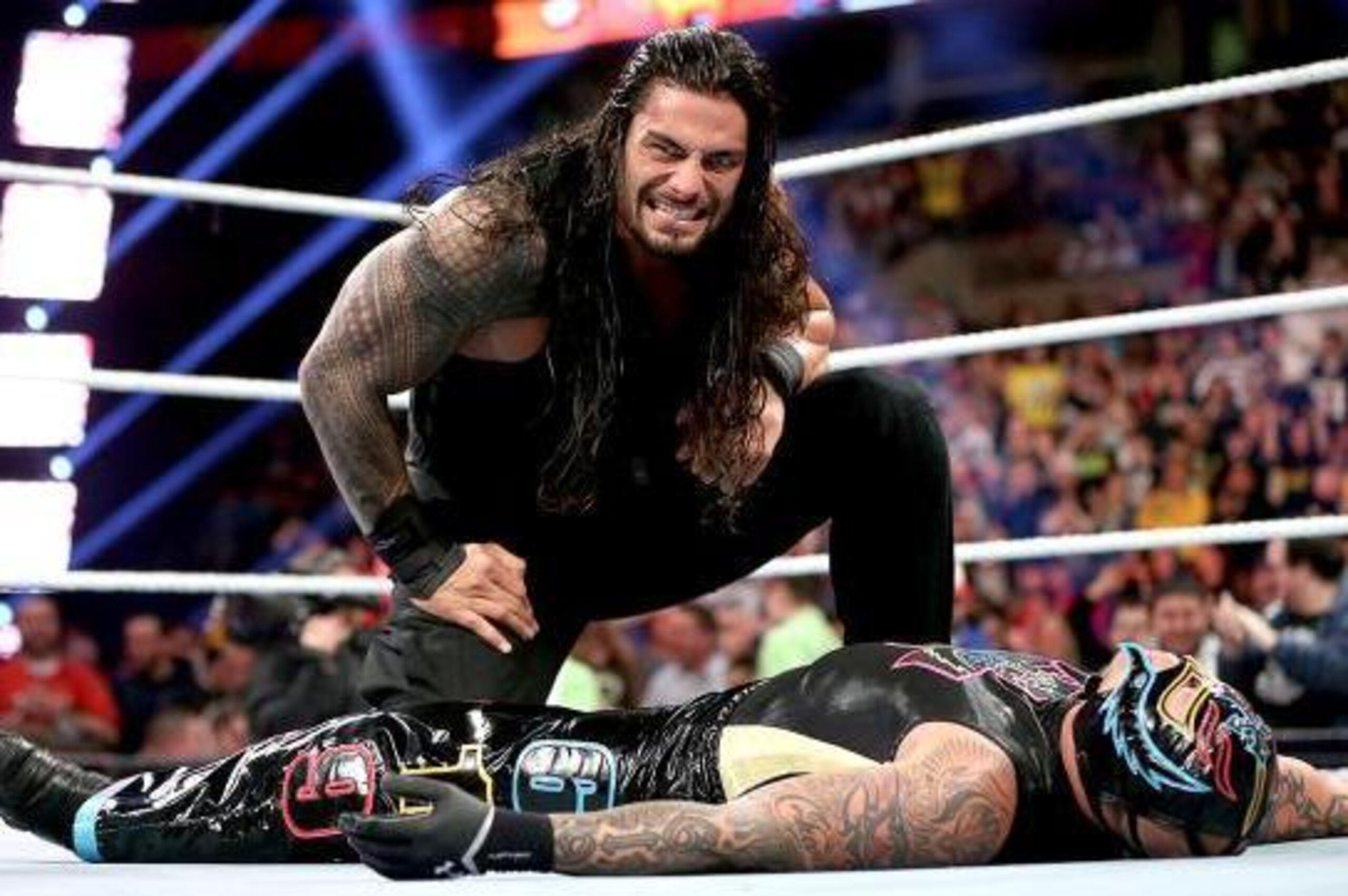 Roman Reigns kneels over the limp body of Rey Mysterio. Roman Reigns kneels over the limp body of Rey Mysterio.