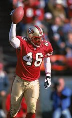 Tim McDonald holds up one of his 20 career interceptions with the 49ers.