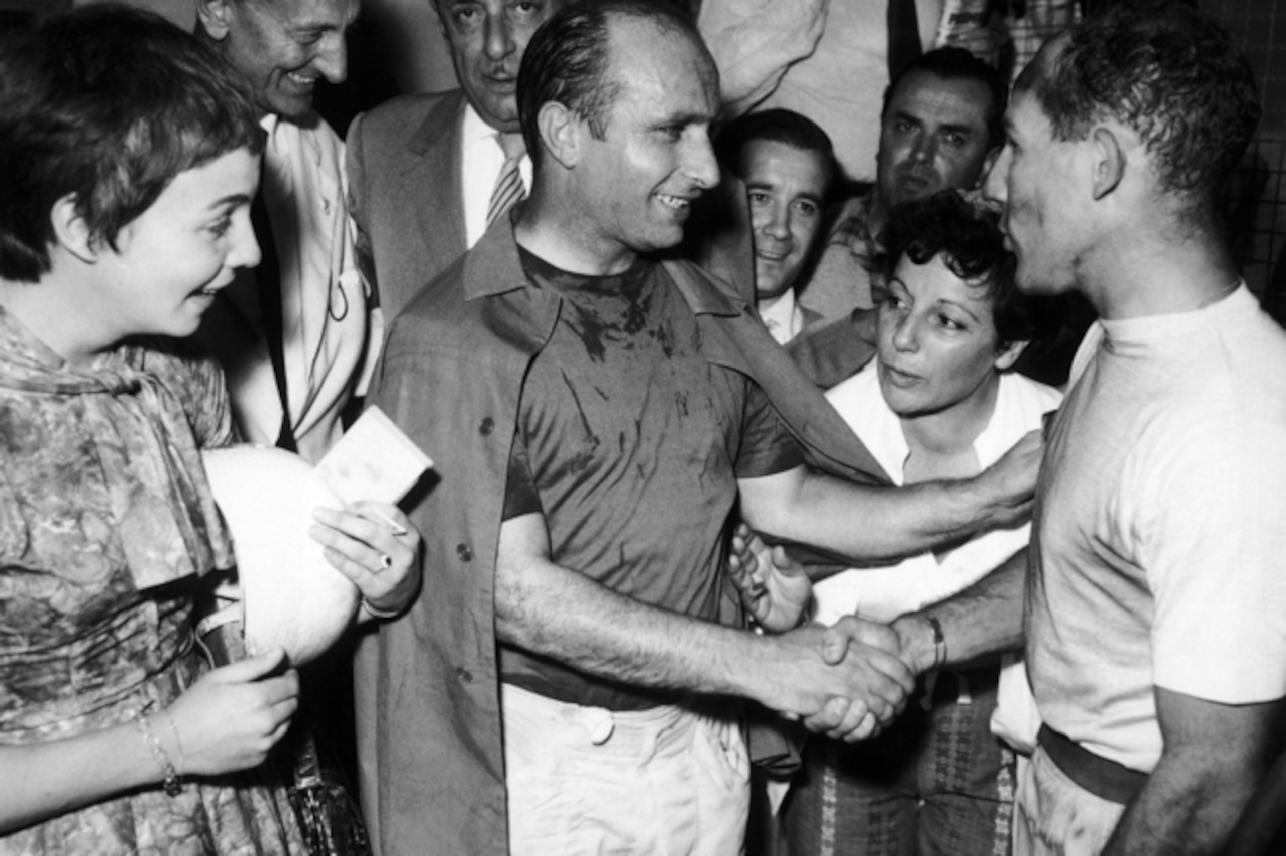 Fangio (middle) congratulates Stirling Moss after Moss' victory at the 1957 Italian Grand Prix.