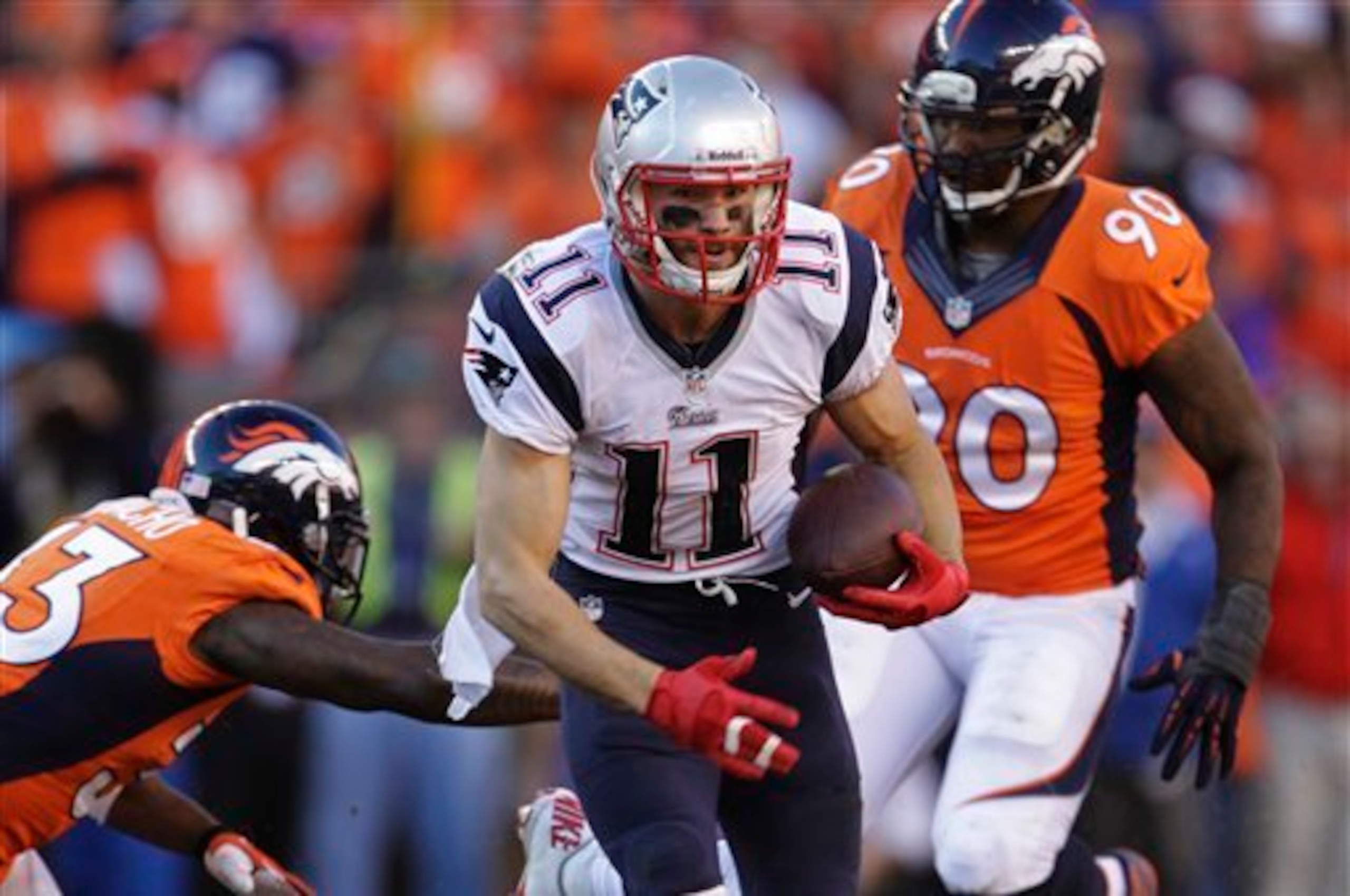 New England Patriots wide receiver Julian Edelman (11) carries the ball past Denver Broncos strong safety Duke Ihenacho (33) and Denver Broncos defensive end Shaun Phillips (90)during the second half of the AFC Championship NFL playoff football game in De
