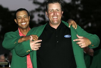 2005 Masters Champion Tiger Woods helps Phil Mickelson the 2006 Masters Champion with the green jacket.
